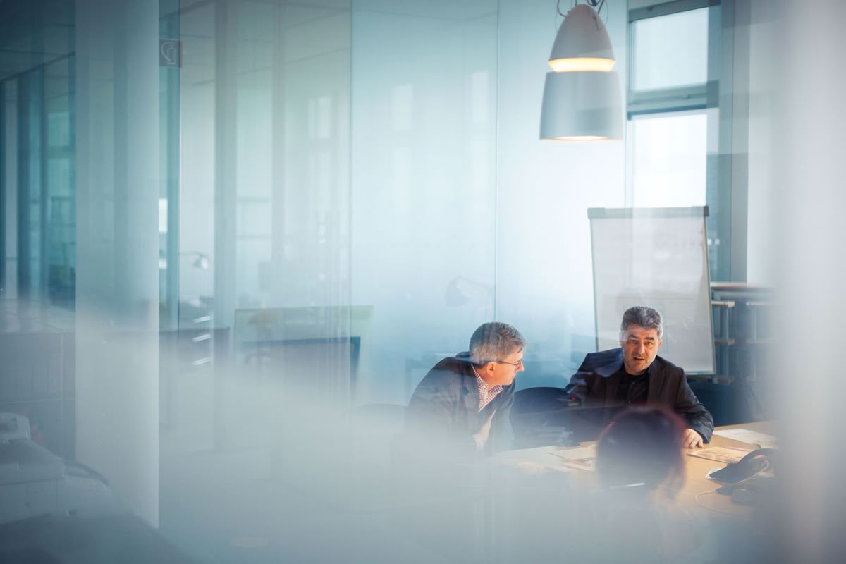 Legal professionals discussing a matter in a glass-walled meeting room